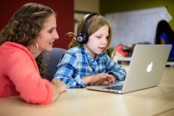 teacher helping student take online language test.